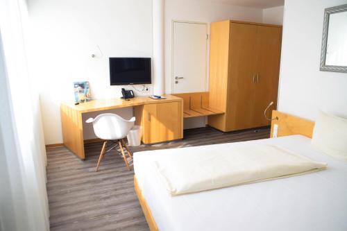 een slaapkamer met een bed en een bureau met een computer bij Cristall Hotel in Waghäusel