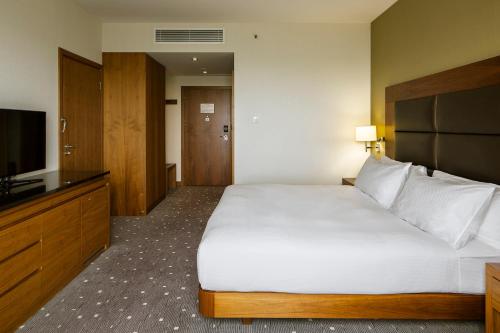 a hotel room with a large bed and a television at DoubleTree by Hilton Łódź in Łódź