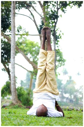 a man laying in the grass with his feet on his head at Vajra Periyar Heritage in Alwaye