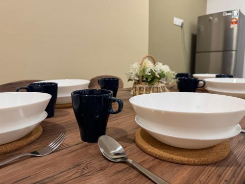 a wooden table topped with white bowls and spoons at NEW-Serene Home Juru Sentral Icon City in Bukit Mertajam