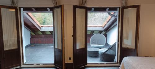 a room with two sliding glass doors and a chair at Hotel Aldori Landetxea - Reserva de la Biosfera Urdaibai - Adults Only in Muxika