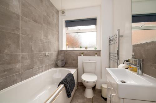 a bathroom with a toilet and a tub and a sink at Ideal 2 Bedroom Ground floor Apartment By Jesswood Properties for Contractors & Business, Free Parking and Wifi in Hinckley