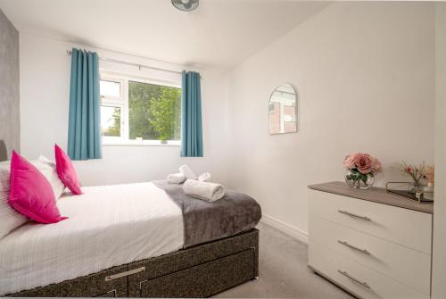 a bedroom with a bed with pink pillows and a dresser at Ideal 2 Bedroom Ground floor Apartment By Jesswood Properties for Contractors & Business, Free Parking and Wifi in Hinckley