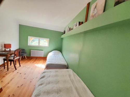 Cette chambre est dotée d'un mur vert et de 2 lits. dans l'établissement Les Ecuries du Château, à Gravigny