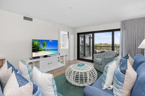 Una sala de estar con un sofá azul y un televisor en Pelicans Roost 106 condo, en Sanibel