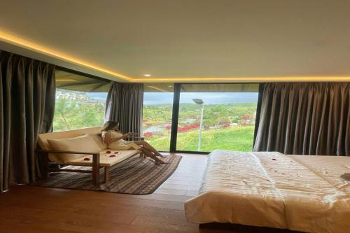 a woman sitting in a chair in a bedroom with a large window at BonBon Villa & Coffee in Bảo Lâm