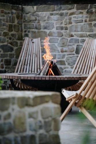 a fire pit with two benches next to a fireplace at Le Temps de Vivre Chimay - Ardennen in Momignies