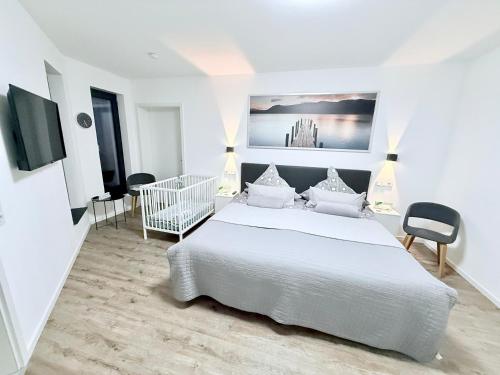 a white bedroom with a large white bed and chairs at FeWo Mosel - Comfort & Relax in Treis-Karden