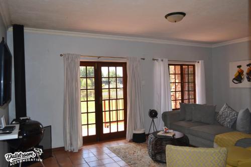 a living room with a couch and two sliding glass doors at The Yems in Dullstroom