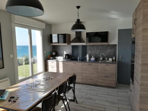 une cuisine avec une table et des chaises ainsi qu'une grande fenêtre dans l'établissement La maison de la plage 4 étoiles en front de mer SPA intérieur GR34, à Plouarzel