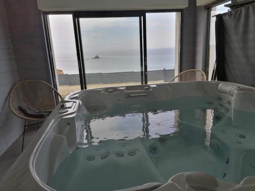 d'une baignoire avec vue sur l'océan. dans l'établissement La maison de la plage 4 étoiles en front de mer SPA intérieur GR34, à Plouarzel
