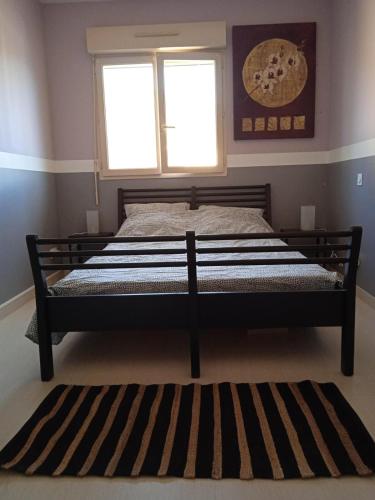 - un lit dans une chambre dotée d'une fenêtre et d'un tapis dans l'établissement Chez Malya, maison au calme, proche du lac, à Charavines