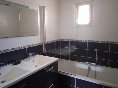 une salle de bain avec un lavabo, un miroir et une baignoire dans l'établissement Chez Malya, maison au calme, proche du lac, à Charavines