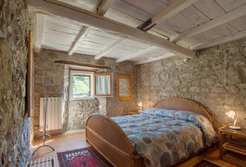 - une chambre avec un lit et un mur en pierre dans l'établissement Fattoria Ca' di Fatino, à Castiglione dei Pepoli