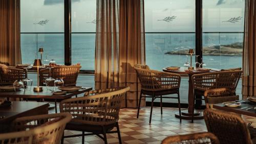 a restaurant with tables and chairs and a view of the ocean at AX ODYCY Hotel in St Paul's Bay