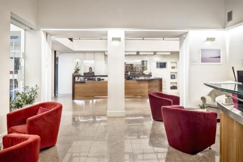 an office lobby with red chairs and a counter at Hotel Italia in Cagliari