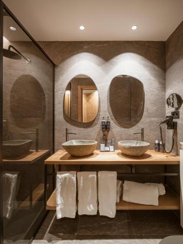 a bathroom with two sinks and two mirrors at The Mountains Hotel in Sierra Nevada