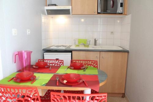 - une cuisine avec une table et des chaises avec des bols rouges dans l'établissement Appt 2 pièces LA ROCHELLE - LR030-C115, à La Rochelle