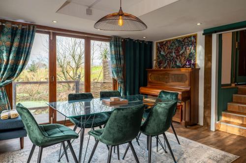 a dining room with a glass table and green chairs at Heron's Perch- A pond-side retreat with cinema room in Callington