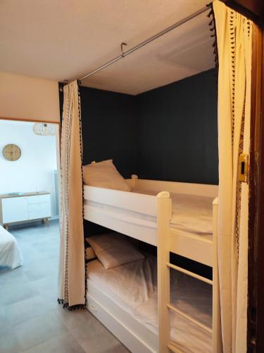 - une chambre avec 2 lits superposés et des rideaux dans l'établissement Studio avec coin nuit à deux pas de la plage, à Mauguio
