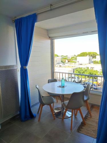 une table et des chaises dans une pièce avec une fenêtre dans l'établissement Studio avec coin nuit à deux pas de la plage, à Mauguio