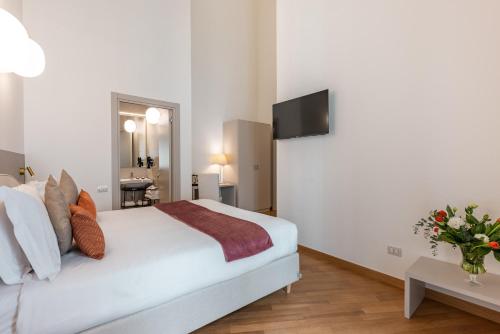 a bedroom with a white bed with a tv on the wall at Palazzo Indelli in Monopoli