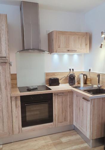 une cuisine avec des armoires en bois et un four à plaques de cuisson dans l'établissement L'Oasis de Fougères, à Fougères