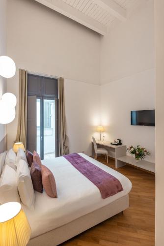 a white bedroom with a large bed and a desk at Palazzo Indelli in Monopoli