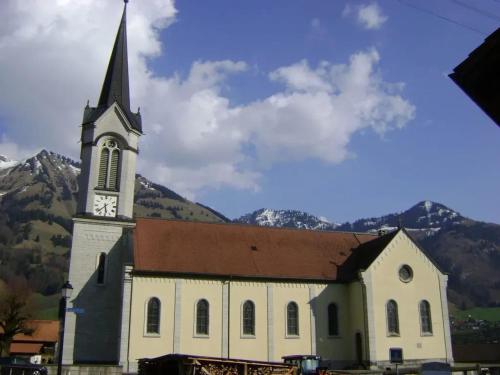 a church with a clock tower with mountains in the background at Cozy Apartment in Haut-Intyamon with Garden 75 m² in Albeuve