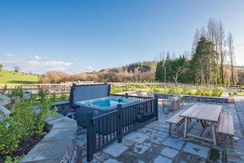 a patio with a hot tub and a picnic table at Cofford Farm in Exeter