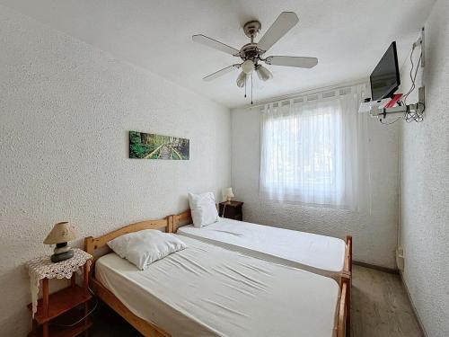 une chambre avec deux lits et un ventilateur de plafond dans l'établissement 3548-Appartement à 100m de la plage, à Argelès-sur-Mer