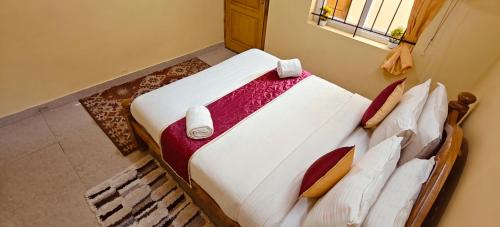 a bedroom with a bed with white sheets and pillows at Kodai Hillscape in Kodaikānāl
