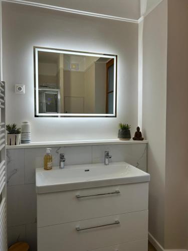 une salle de bain avec un lavabo blanc et un miroir dans l'établissement Belle maison de ville au centre de Luchon, à 200m des Télécabines !, à Luchon