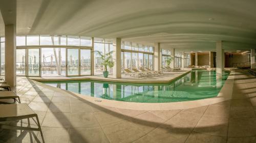 a large swimming pool in a building with windows at AX ODYCY Hotel in St Paul's Bay