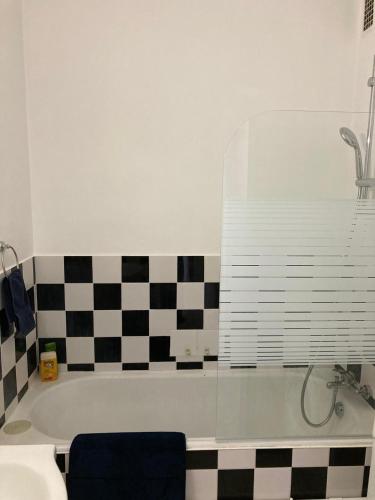La salle de bains est pourvue d'une baignoire et d'un mur en damier. dans l'établissement パリ16区 改装したばかりのアパルトマン クーラー付, à Paris