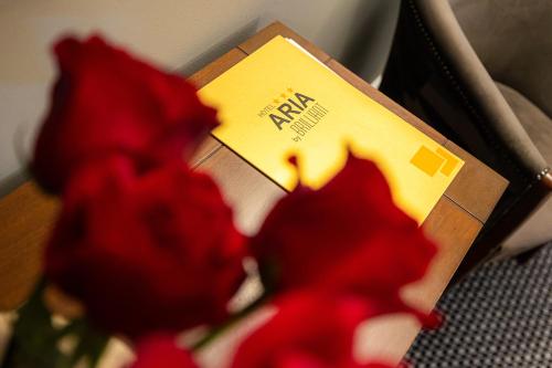 a vase of red flowers next to a box at Aria by Brilliant in Zalău