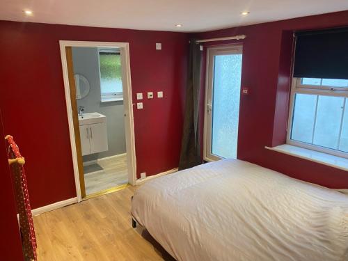 イーストボーンにあるBasement Flat in the town centre!の赤い壁のベッドルーム1室、ベッド1台、バスルームが備わります。
