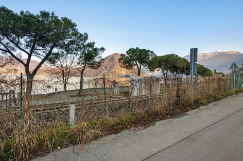 a fence on the side of a road with trees and mountains at Lake and Love - Lago D'Iseo in Sulzano