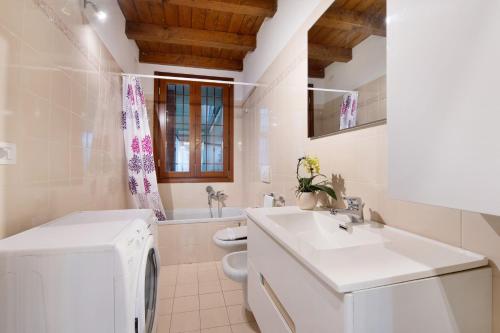 a white bathroom with a sink and a washing machine at Lake and Love - Lago D'Iseo in Sulzano