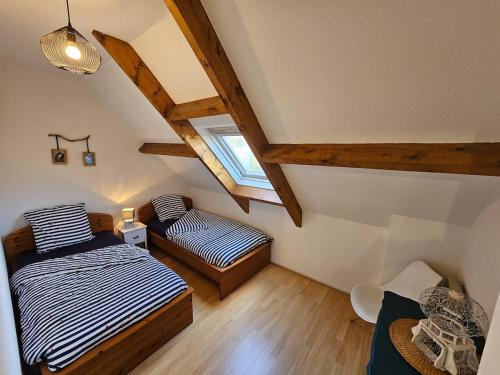 une chambre mansardée avec deux lits et une fenêtre dans l'établissement Les Embruns, à Clohars-Carnoët