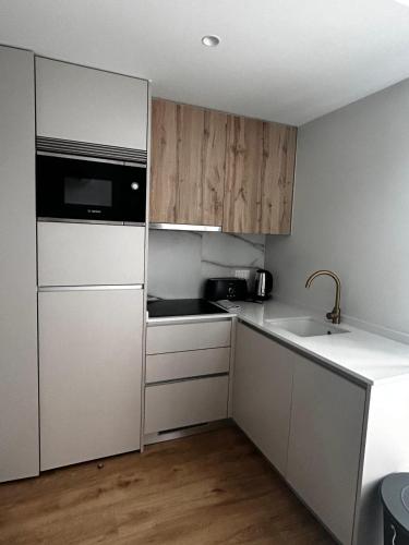 a kitchen with white cabinets and a sink and a microwave at NEW Douro 901 Mezzanini with parking in Vila Nova de Gaia