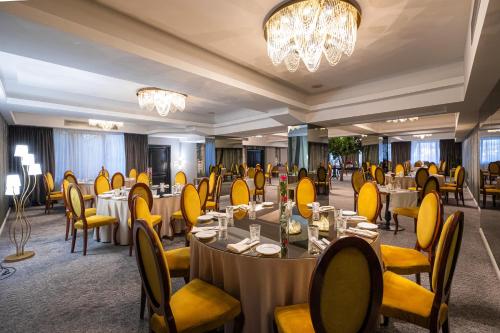 a dining room with tables and chairs and a chandelier at Aria by Brilliant in Zalău