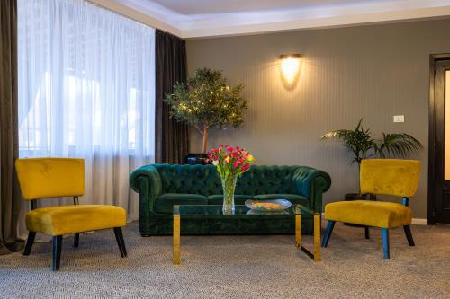 a living room with a green couch and two chairs at Aria by Brilliant in Zalău