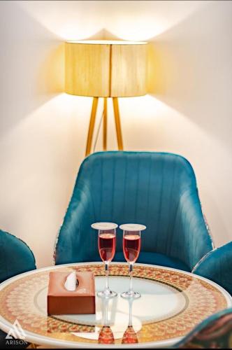 two glasses of wine on a table with a blue chair at Arison Luxury in Srinagar