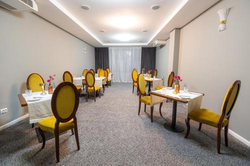 a dining room with tables and yellow chairs at Aria by Brilliant in Zalău