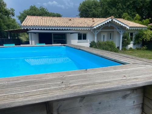 une piscine bleue avec une maison en arrière-plan dans l'établissement Villa OLYMPE & son T2, à Andernos-les-Bains