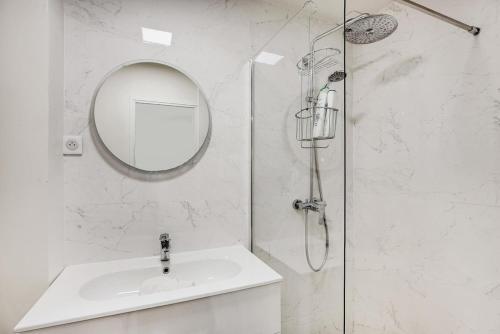 une salle de bain blanche avec un lavabo et un miroir dans l'établissement LE MARAIS - NEW APARTMENT Haut de Gamme, à Paris