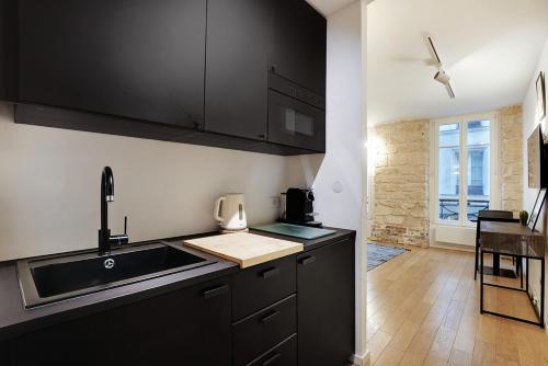 - une cuisine avec des placards noirs et un évier dans l'établissement LE MARAIS - NEW APARTMENT Haut de Gamme, à Paris