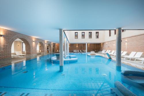 a large swimming pool with chairs in a building at Castilla Termal Olmedo in Olmedo