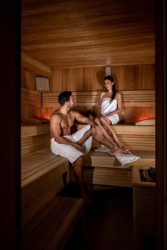 a man and woman sitting in a sauna at Coco Boutique Hotel & Spa in Karpacz